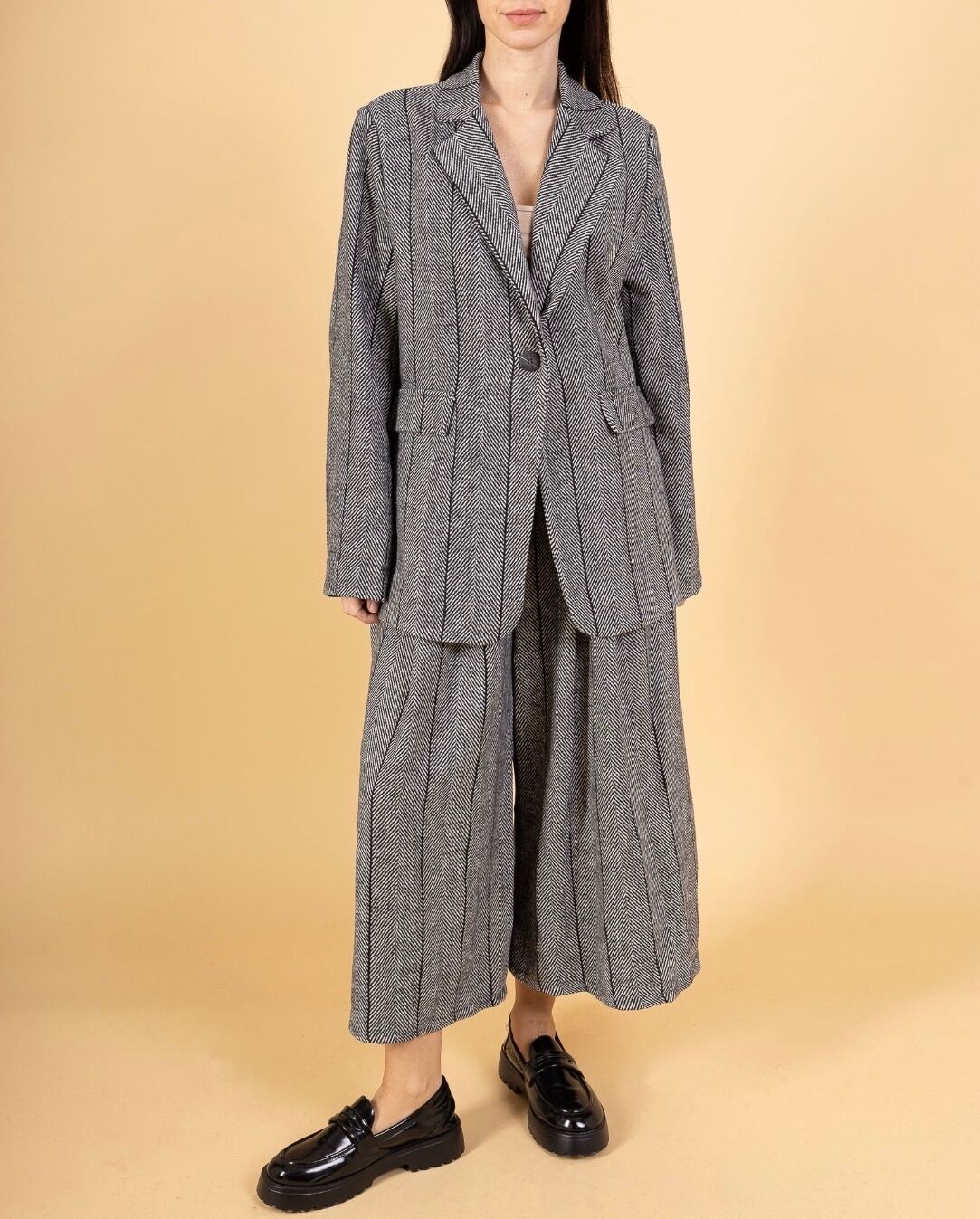 Veste blazer tailoring col tailleur à revers fermeture simple par un bouton , 2 poches à rabat sur le devant , tissu texturé motif chevrons fines rayures verticales noires