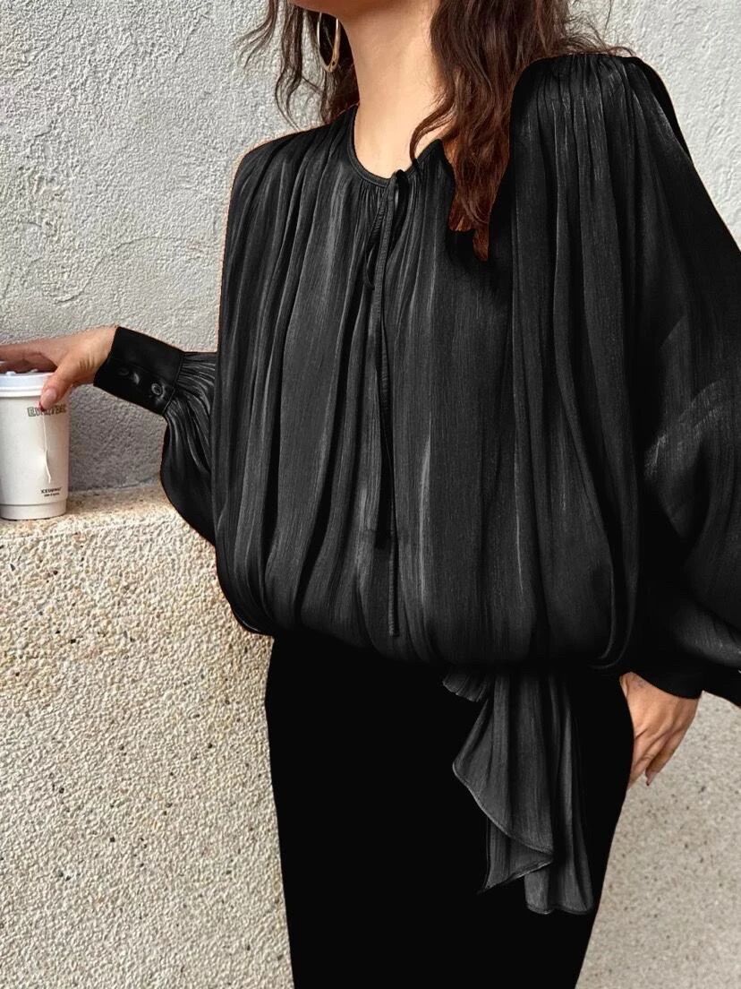 Flowy pleated blouse with a round neck and tie.