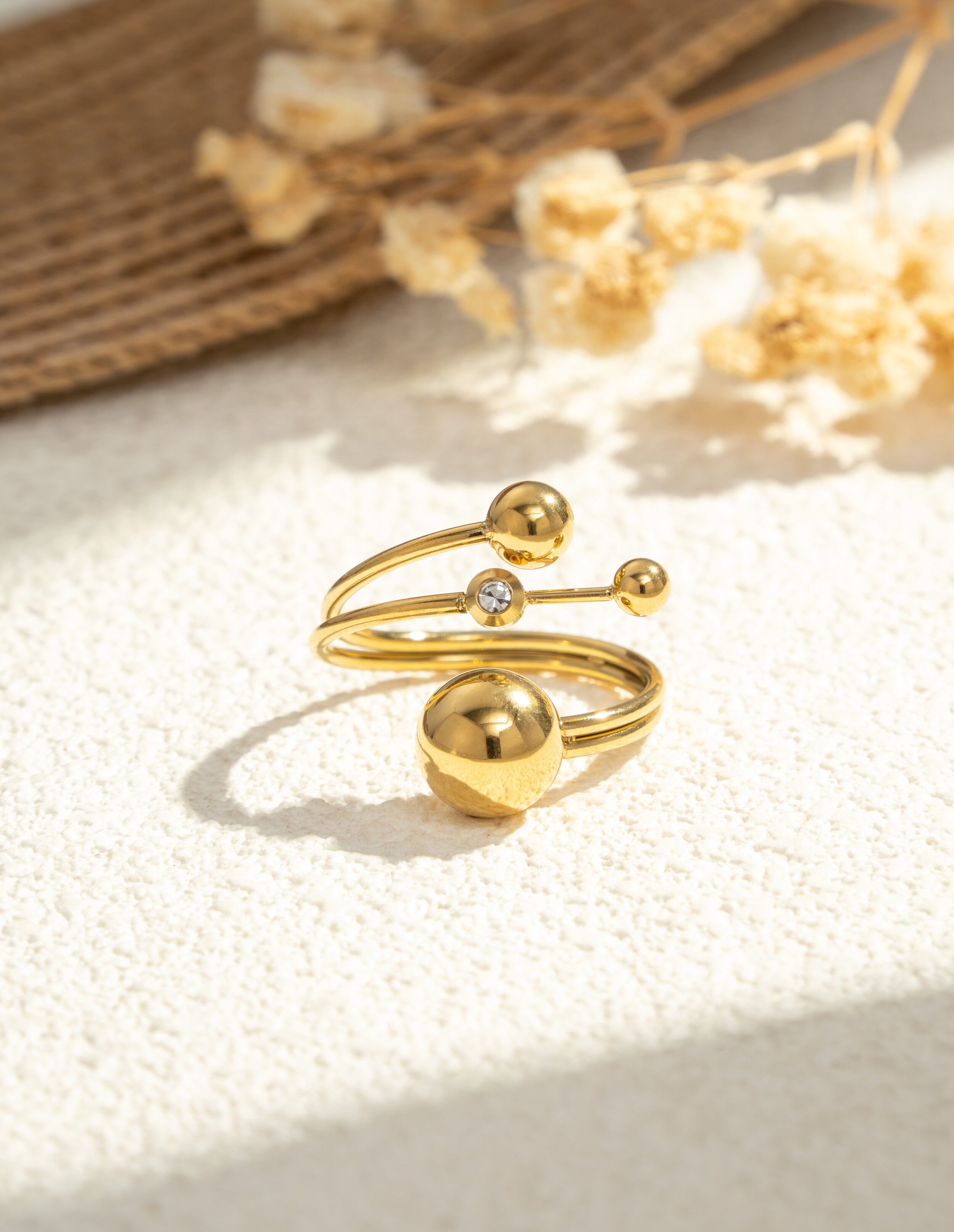 Vergoldeter Ring mit drei modernen Kugeln und einem eingelegten Leuchtstein, Edelstahl