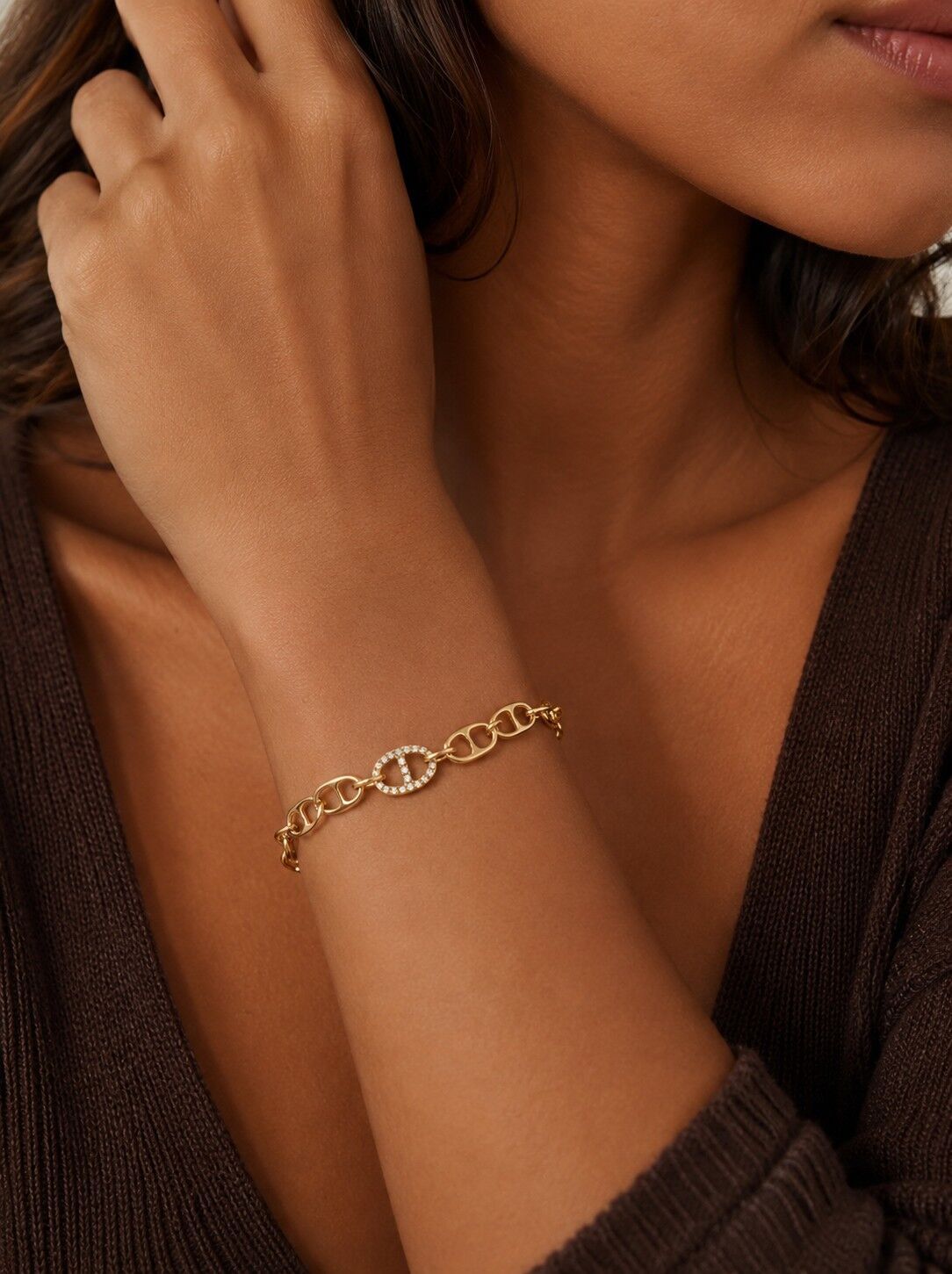 Goldfarbenes Armband mit ovalen Gliedern, zentralem, mit Steinen besetztem Motiv, elegantes, modernes Design