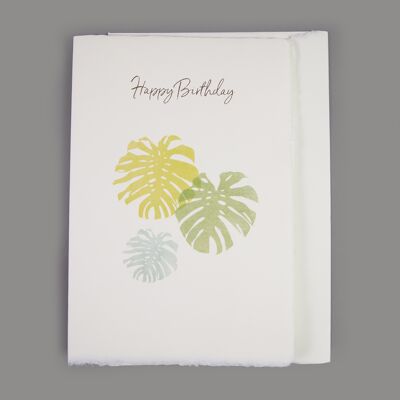 Tarjeta de papel hecha a mano "Feliz cumpleaños" con hojas de filodendro
